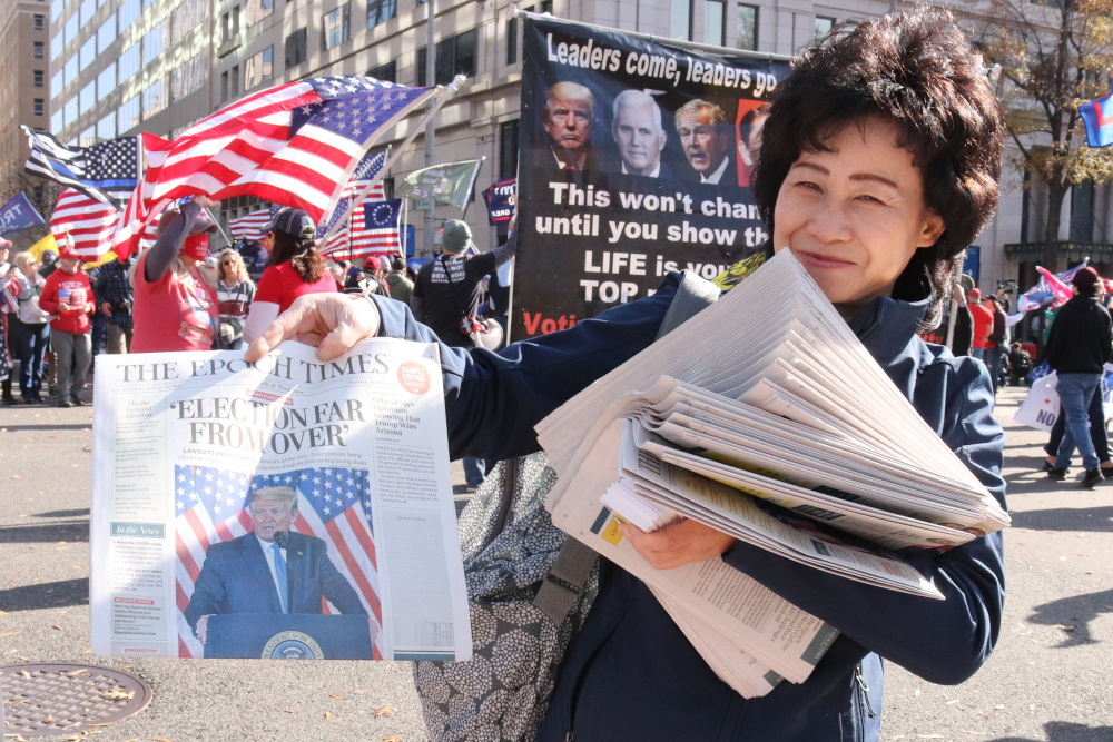 Election denial: Woman holds Epoch Times at Maga rally