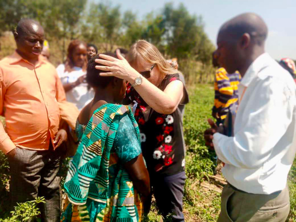 Praying for a new Christian in an agricultural project on the outskirts of Kigali